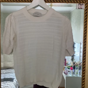 Vit blus med puffärm från Neo Noir - Supersöt vit blus från Neo Noir med korta puffärmar och diskret hålmönster. Storlek S/M