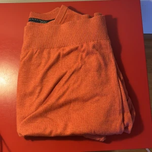 Orange v-ringad tröja Tommy Hilfiger - Säljer en orange v-ringad tröja från Tommy Hilfiger i storlek M. Tröjan är tillverkad i en mjuk mix av pima bomull och kashmir, har långa ärmar och ribbade muddar. Klassisk liten logga broderad på bröstet.