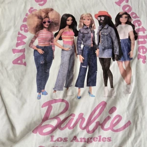 T-shirt med tryck! - Vit t-shirt med stort Barbie-tryck i rosa och motiv av fem Barbiedockor på baksidan. Texten 'Always Stronger Together' och 'Barbie Los Angeles California, 1959' i rosa. Skön oversized tshirt i stl M från Bershka med coolt tryck på ryggen! Perfect till att croppa den / tuck up one side dör en mer Street vibe! Skriv om du har några frågor eller är intresserad!☀️🫶