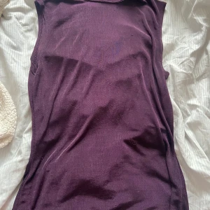Mörklila ärmlös topp från Flash - Säljer en mörklila ärmlös topp från Flash i storlek S. Toppen är i ett tunt material som gör den lite genomskinlig och har en enkel, rak passform. Perfekt för sommaren. 