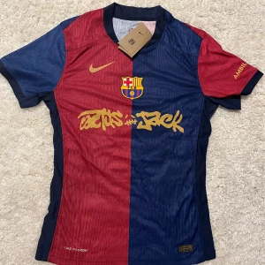 FC Barcelona X Cactus Jack Lamine Yamal Nike tröja - Helt ny aldrig använt innan. FC Barcelona x Cactus Jack matchtröja med Lamine Yamal 19 på ryggen. Halva tröjan är röd och andra halvan marinblå, med gul Nike-logga och klubbmärke på bröstet. Tryck i gult framtill och på ryggen. Tillverkad i lätt Dri-FIT-material för maximal komfort.