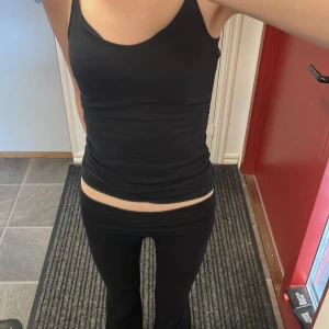 2 svarta linnetoppar med smala axelband - Enkel och stilren svart linnetopp med smala, justerbara axelband. Toppen är figurnära och har en klassisk rak skärning. Den har dubbelt tyg över bröstet. Perfekt att matcha med jeans eller kjol för en clean look. Mjuk och stretchig bomullskänsla. 30kr för båda