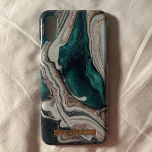 Två iDeal of Sweden mobilskal - Säljer två snygga mobilskal från iDeal of Sweden. Ena har ett marmormönster i grönt, det andra med blommigt motiv med blå orkidéer på vit bakgrund. Båda har en stilren metallogo längst ner.