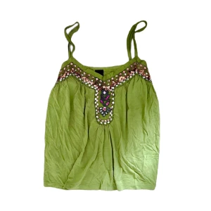 Grön paljettlinnetopp Soaked in Luxury - Supersöt ljusgrön linnetopp från Soaked in Luxury med tunna axelband och v-ringning. Toppen har glittriga paljettdetaljer i roliga färger. Perfekt til sommaren! Bild 1 representerar plaggets färg bäst!