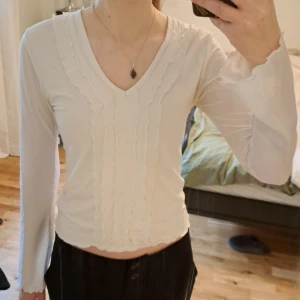 Vit långärmad meshtopp från Flash - Vit långärmad topp från Flash med v-ringning och dekorativa vågiga sömmar framtill. Tyget är i mesh och därav är toppen lite genomskinlig. Men tröjan har dubbla lager framtill så den inte är genomskinlig där. Om ni vill se fler bilder eller har en fråga är det bara att höra av sig <3