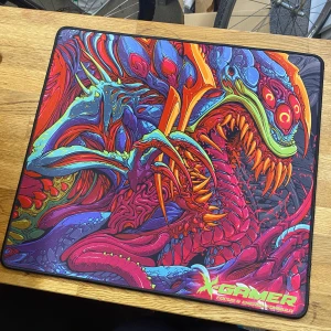 Musmatta  - Bilderna visar en färgstark och detaljerad musmatta med ett monsterliknande motiv och texten 'XGAMER Focus & Energy Formula'. Det finns ingen bok på bilderna, utan endast en gamingmusmatta med cool design som passar perfekt för gamers. Troligtvis från x game