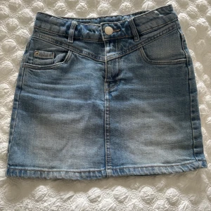 Ljusblå jeanskjol från LAB Industries - Snygg ljusblå jeanskjol från LAB Industries. Kjolen är ganska kort och har storlek 134, men passar även några storlekar över. Man kan även vika ner överkanten om man skulle vilja det. Perfekt till sommaren!☀️🌅(kjolen är i barnstorlek)