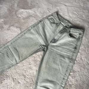 Ljusgrå raka jeans från Gina Tricot - Säljer ett par ljusgrå jeans från Gina Tricot med klassisk femficksmodell och raka ben. Jeansen har en snygg tvättad look och normalhög midja. 