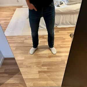 Levi's 511 mörkblå jeans straight fit - Mörkblå Levi's 511 jeans med klassisk femficksdesign och diskret slitning på låren. Jeansen har rak passform och normal midja, tillverkade i mjukt denimtyg. Perfekta för en clean och stilren look. W30 L32