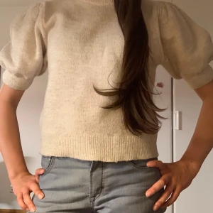 Stickad t-shirt - Beige/krämvit stickad t-shirt med puffärm, från Gina Tricot. Köpt förra sommaren men inte använd så mycket💕 Strl 170, passar mig som brukar ha S.