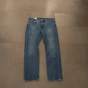 Levis 502 blå jeans straight fit - Klassiska Levis 502 w32 L30 jeans i blå denim med raka ben och normal passform. Byxorna har fem fickor, knappgylf och snygga kontrastsömmar. Perfekta för en avslappnad och tidlös stil. 