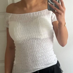 Vit offshoulder smockad topp - Säljer en söt vit topp med smockad struktur och offshoulder-design. 💓💓