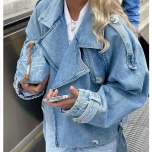 jeansjacka från Meotine - Säljer en ljusblå oversized jeansjacka från Meotine. Jackan har breda slag, dubbelknäppning, bälte i midjan och stora fickor. Snygga detaljer med knappar på ärmslut och axlar. Perfekt för dig som gillar en chill och trendig look. Kom med prisförslag! 