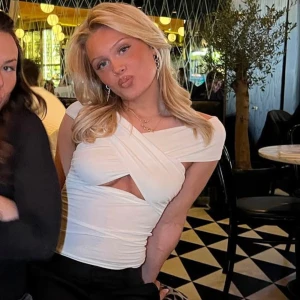 Vit omlott topp med cut-out detalj - Säljer en vit omlott topp med snygg cut-out detalj framtill. Toppen har korta ärmar och en figurnära passform som framhäver siluetten. Perfekt för dig som vill sticka ut med en trendig och stilren look.