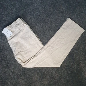 Beiga linnebyxor från H&M, regular fit - Snygga beiga linnebyxor från H&M i regular fit, Storlek M. Byxorna har elastisk midja och är tillverkade i en skön linnemix som passar perfekt för varmare dagar. Stilren och enkel. Aldrig använda med taggarna kvar
