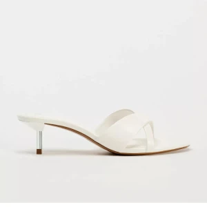 Vita högklackade från Zara - Snygga vita sandaler från Zara med smala korsade remmar och låg klack i metall-look. Skorna har öppen tå och platt sula framtill. Tillverkade i syntetmaterial med extra komfort tack vare Airfit-innersula. Perfekta för dig som gillar stilren och modern design.