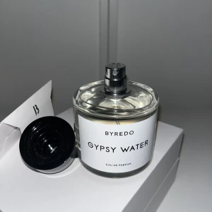 Byredo Gypsy Water Eau de Parfum - Byredo Gypsy Water Eau de Parfum i stilren, rund glasflaska med svart lock och vit etikett. Parfymen kommer i originalförpackning med tillhörande box och kort. Doften är ikonisk och unisex, perfekt för dig som gillar exklusiva och fräscha parfymer.