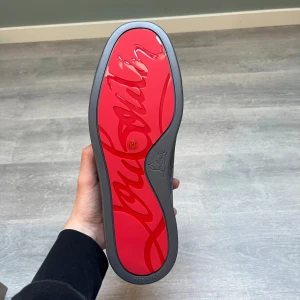 Christian Louboutin svarta sneakers mocka - Snygga svarta sneakers från Christian Louboutin i mjuk mocka med klassisk röd sula och guldfärgad logga på innersulan. Skorna har rund tå, snörning och diskret design som ger en lyxig känsla. Kommer med originalkartong, dustbag och tillbehör.