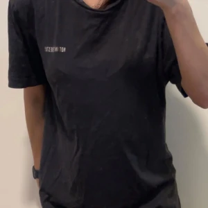 Svart t-shirt med Lisa Simpson-tryck - Svart ikonisk tshirt i bomull med tryck av Lisa Simpson på ryggen och texten 'NOT INTERESTED!' på bröstet. Storlek S/M