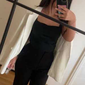 Vit kavaj med svarta byxor - Snygg vit kavaj med klassisk passform, perfekt att slänga över axlarna. Matchas med svarta höga byxor och svart topp för en stilren look. Kavajen har enkla knappar och rena linjer som ger en modern känsla. Med prislappen kvar 