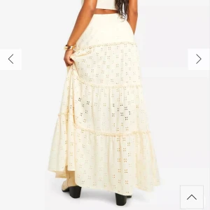 Beige långkjol med broderade detaljer - Helt slutsåld och säljs ej av dem mer!Säljer en beige långkjol med broderade hålmönster och volanger. Kjolen har en luftig och flowy passform, perfekt för varma dagar. Den är tillverkad i ett lätt material och har en romantisk boho-vibe.