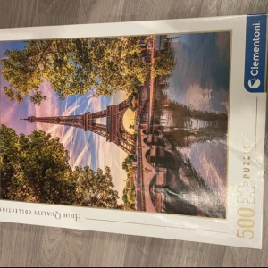 Clementoni pussel med Eiffeltornet - Säljer ett Clementoni pussel med 500 bitar som föreställer Eiffeltornet i Paris vid Seine, omgiven av grönskande träd och vacker himmel. Perfekt för dig som gillar utmaningar och fina motiv.  Kartonen är lite skadad men pusslet är hur fint som helst!