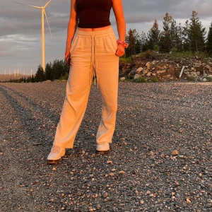 Beigea linnebyxor  från Vero Moda - Beiga linnebyxor från Vero Moda med knytning i midjan och raka ben. Byxorna har en avslappnad passform, perfekt nu till sommaren 