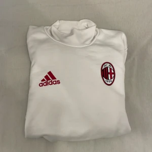 AC Milan långärmad fotbollströja från Adidas - Vit långärmad AC Milan fotbollströja från Adidas med röda och svarta ränder längs ärmarna. Broderad AC Milan-logga och Adidas-märke på bröstet. Tillverkad i ClimaCool-material för bra ventilation. Kan gå ner i pris!!!
