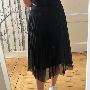 Svart plisserad midikjol Bershka - Säljer en svart plisserad kjol med midilängd. Kjolen har ett tunt, lätt material och bred linning i midjan. Perfekt för dig som gillar en klassisk och stilren look.