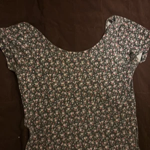 Blommig topp från Bik Bok - Supersöt blommig topp från Bik Bok i storlek S. Den har korta ärmar och ett småblommigt mönster i rosa och vitt på en mörk botten. Perfekt för vår och sommar!