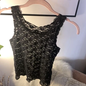 Svart spetslinne från Gina Tricot - Säljer ett svart linne från Gina Tricot i genombruten spets. Linnet är ärmlöst och har en fin, feminin spetskant runt halsringningen. Perfekt att styla lager på lager eller som det är.💕💐