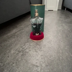 Jean Paul Gaultier Le Beau Eau de Toilette - Parfymflaska formad som en manlig torso i blågrönt glas med gulddetaljer. Kommer med en grön metalltub och röd sammetsbas. Doften är fräsch och maskulin, perfekt för dig som vill sticka ut.