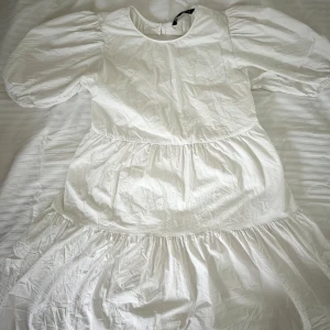 Vit puffärmklänning från Zara - Superfin vit klänning från Zara med puffärmar och rund halsringning. Klänningen har öppen rygg med knytband och volangdetaljer i kjolen. Perfelt till studenten. Köpt second hand och aldrig använd av mig. Jättelitet märke som kan synas på sista bilden 