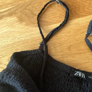 Svart smockad klänning från Zara - Kan sälja för mindre så kom privat, Säljer en svart smockad klänning från Zara med tunna axelband och rynkad struktur. Klänningen har en enkel och stilren design, perfekt för varma dagar. Lätt och luftig modell som ger en avslappnad känsla.🩷