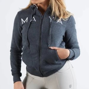 Mörkgrå zip från Maya Delorez - Mörkgrå zip med huva från Maya Delorez. Mjuk insida, två fickor fram och ribbade muddar vid ärmslut och nederkant.