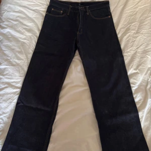 Mörkblå Levis 507 jeans - Säljer ett par mörkblå Levis 507 jeans med raka ben. Jeansen har gylf med knappar och tydliga kontrastsömmar. Uppsydda längst ner.