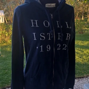 Mörkblå zip-up från Hollister - Mörkblå zip-up från Hollister med dragkedja. Tröjan har huva med söta små rosa blommor💙💤🌸Välanvänd men väldigt skön! Det är bara att skriva om man har frågor!😊💖