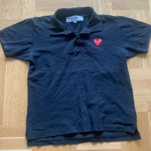 Svart pikétröja från Comme des Garçons Play CDG - Svart pikétröja från Comme des Garçons. Passar perfekt nu när det börjar bli varmare ute. Passar M och S om du vill ha lite oversize. Hör av dig om du undrar något! 
