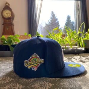 New York Yankees från New Era - En endast testad fåtal gånger Mörkblå New York Yankees keps från New Era med World Series-märke på sidan. En snygg fitted keps från Cooperstown Collection, tillverkad i polyester.