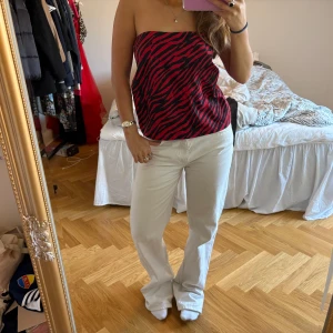 Röd och svart tubtopp från Pull&Bear - Säljer en snygg tubtopp från Pull&Bear i rött och svart zebramönster. Toppen är axelbandslös och har en figurnära passform. Passar perfekt till både jeans och kjol!