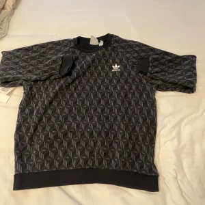 Adidas tröja - Säljer en svart sweatshirt från Adidas med geometriskt mönster och vit logga på bröstet.