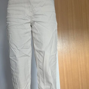 Beige byxor - Säljer ett par stilrena beige byxor med normal passform. Byxorna har en klassisk design med raka ben och är perfekta för en avslappnad look. De är tillverkade i ett bekvämt material som passar bra till vardags.