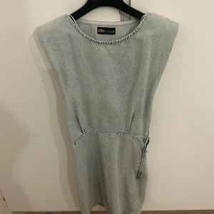 Jeansklänning från Zara - Säljer en super fin ljusblå ärmlös jeansklänning från Zara med markerad midja. Perfekt till sommaren!! 