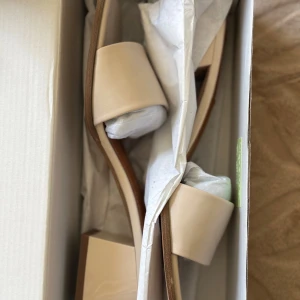 Beige klackskor från NA-KD - Säljer ett par stilrena beige klackskor från NA-KD. Skorna har en blockklack och öppen tå. Aldrig använda. Säljer för 200kr