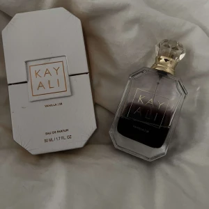 Kayali Vanilla | 28 Eau de Parfum - Elegant parfym från Kayali med en söt och varm vaniljdoft. Flaskan är stilren och genomskinlig med en lyxig guldfärgad kork. Förpackningen är vit och har en modern design. Perfekt för dig som älskar vaniljtoner.