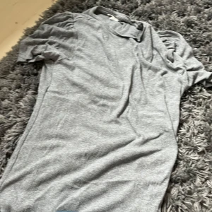 Grå ribbad topp från pomp de lux - Säljer en ljusgrå ribbad topp från Compagnie de Lux i storlek 158-164. Toppen har korta puffärmar och rund halsringning. Perfekt för dig som gillar en enkel men ändå trendig stil.