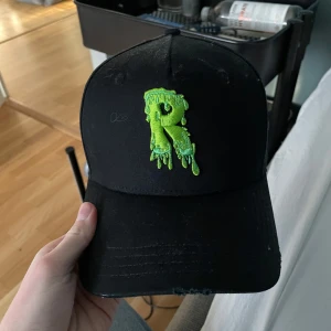 Risky Keps Limited Edition - Cool svart keps med en unik grön broderad design framtill och texten 'RISKY' baktill. Perfekt för att ge din outfit en edgy touch. Justerbar rem för perfekt passform. limited edition finns endast få tak i Sverige, skriv vid minsta lilla fråga pris kan diskuteras!