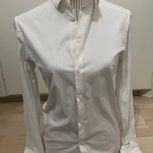 Vit skjorta från Filippa K - Klassisk vit skjorta från Filippa K i tidlös design. Skjortan har lång ärm, knappar framtill. Har användt en två gånger. 