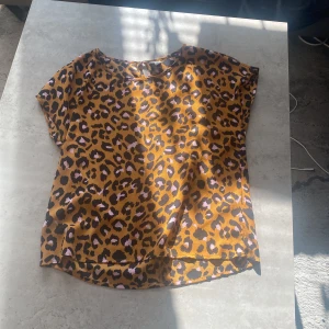 Leopardmönstrad topp från Jacqueline de Yong - Säljer en leopardmönstrad topp från Jacqueline de Yong. Toppen har korta ärmar och en knappdetalj i nacken. Perfekt för att ge din outfit en trendig touch 🐆