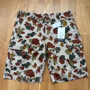Camouflage cargo shorts från Element - Snygga camouflage cargo shorts från Element i beige, grön och brun. De har flera praktiska fickor och en cool design som passar perfekt för sommarens äventyr. Perfekta för dig som gillar en avslappnad stil.
